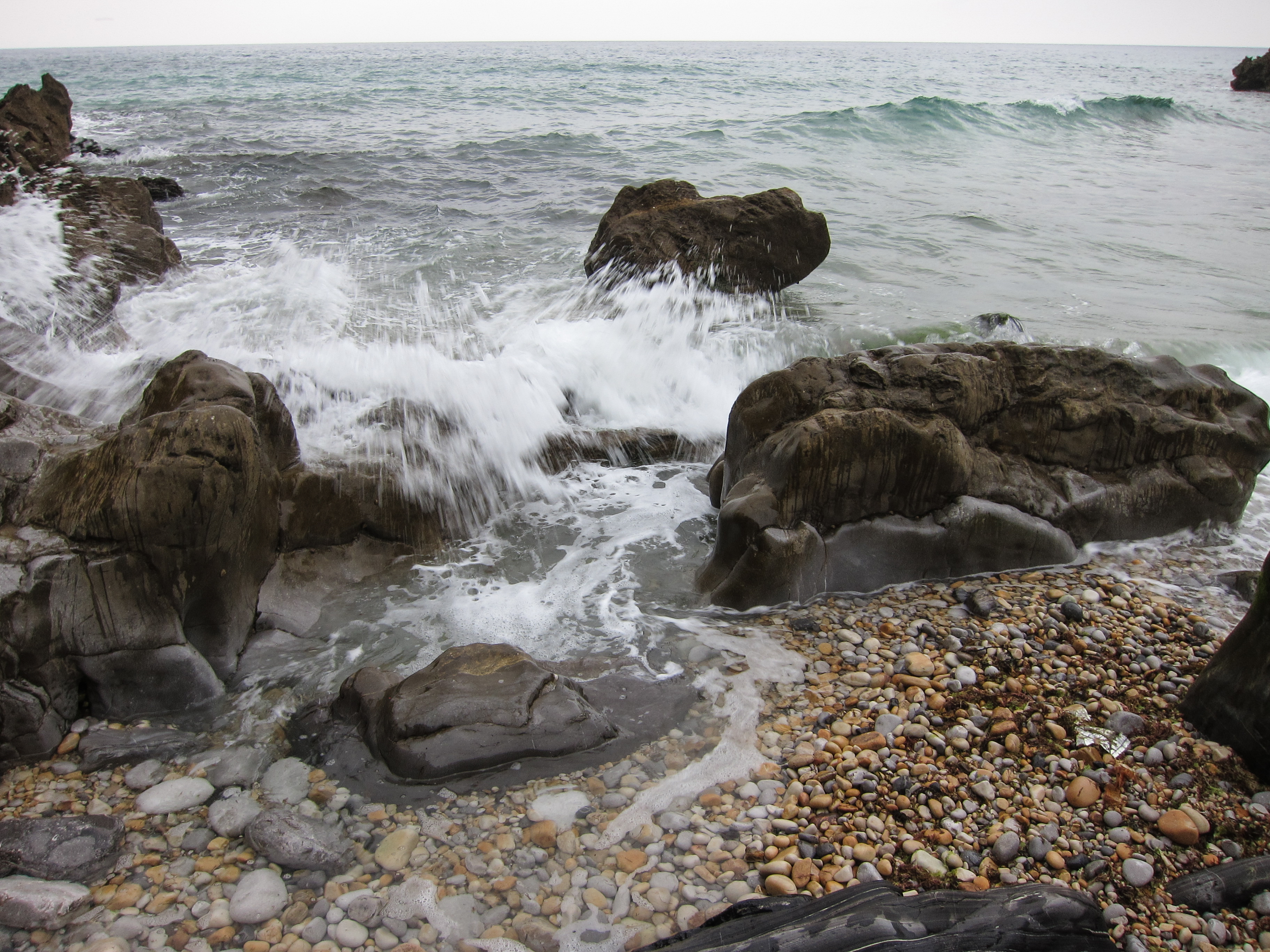 Ola rompiendo entre las rocas