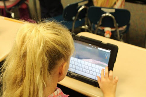 Una niña de primaria trabajando con una tableta en clase