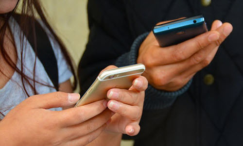 Adulto enseñando a manejar un teléfono móvil a un menor