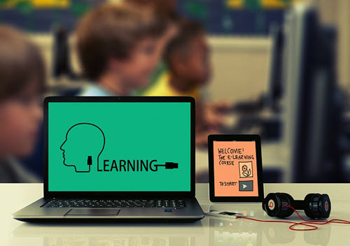 Ordenador portátil con el aula al fondo y la palabra "Aprendizaje", en inglés, en la pantalla